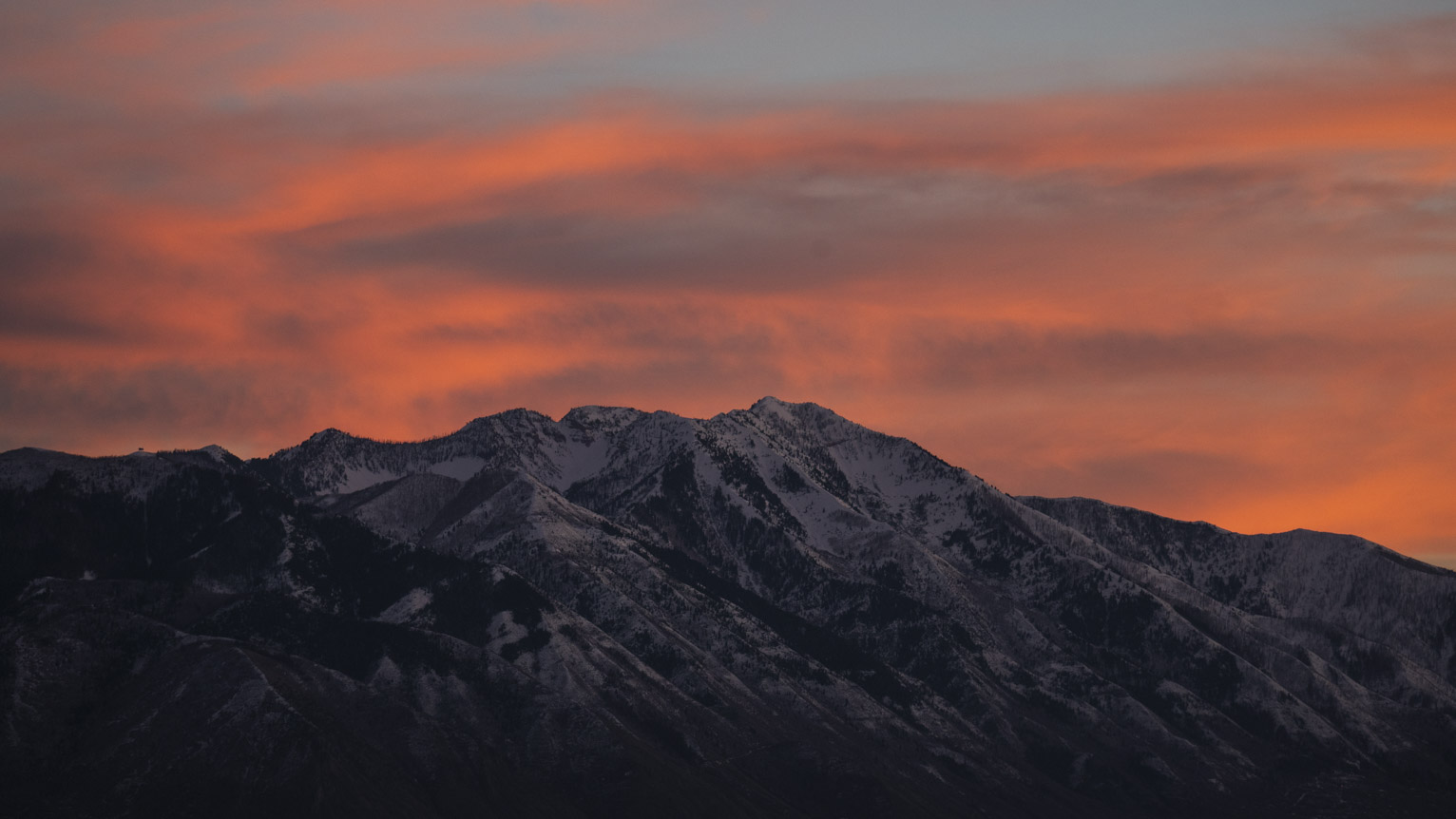 Sunset lit clouds over the snowy mountains